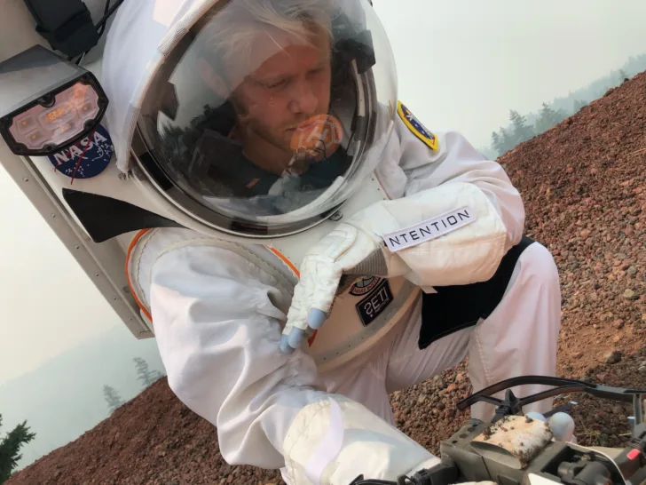 Under felttest for NASA Haughton-Mars Project i 2021 ble nye teknologier for bemannet utforsking av månen og Mars utprøvd i Oregon.Her er Magnus Arveng ved Ntention i romdrakt fra Collins Aerospace for analoge tester under innsamling av prøve vha drone og Ntention Astronaut Smart Glove. Foto: NASA Haughton-Mars Project / Pascal Lee.